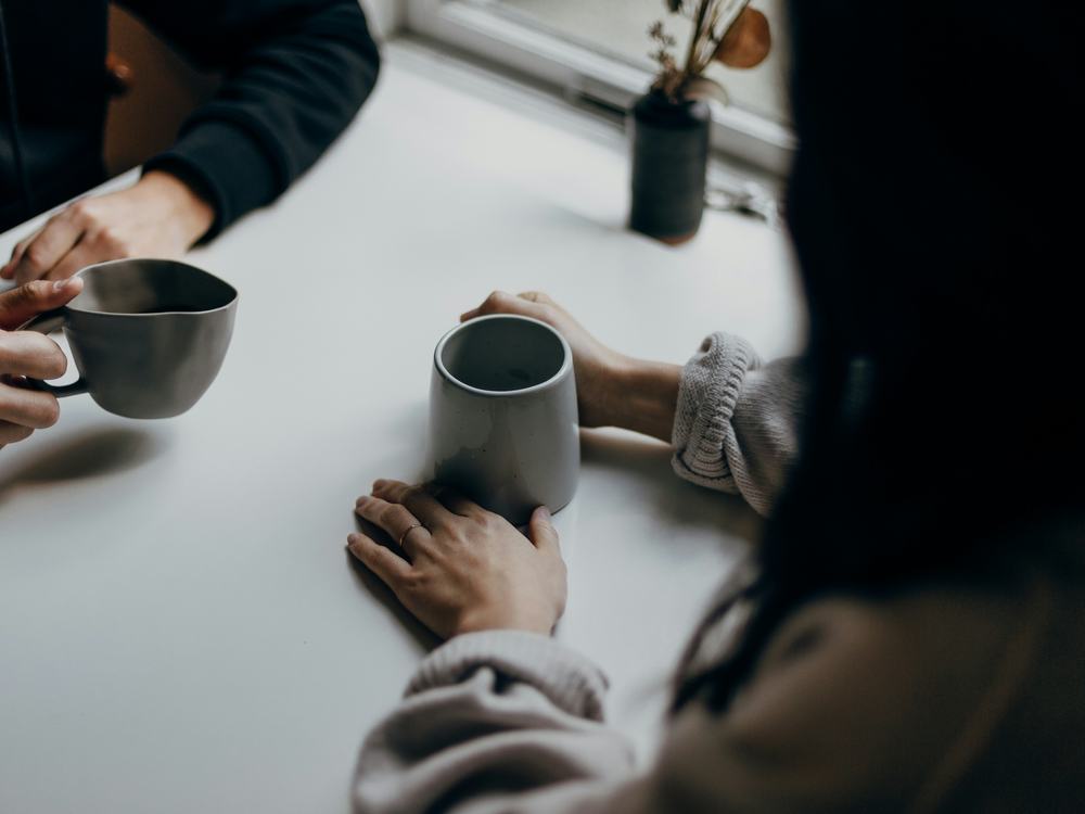 Deux personnes qui discutent à une table, une tasse à la main