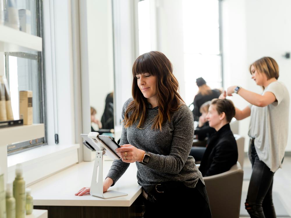 Une femme en pull gris tenant une tablette